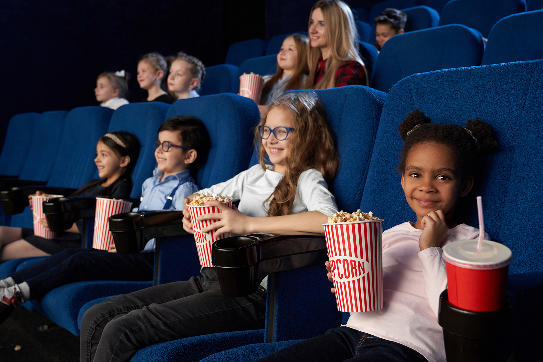 Children enjoying film premiere in movie theatre.